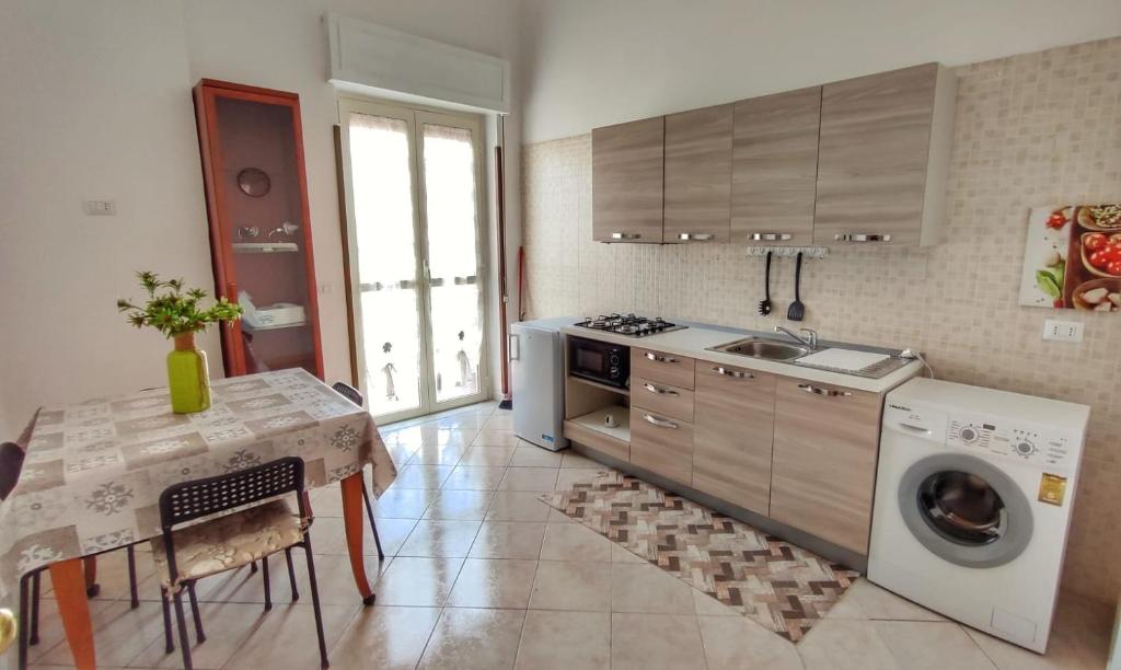 a kitchen with a table and a sink and a washing machine at Confy Apartments Pompei in Pompei