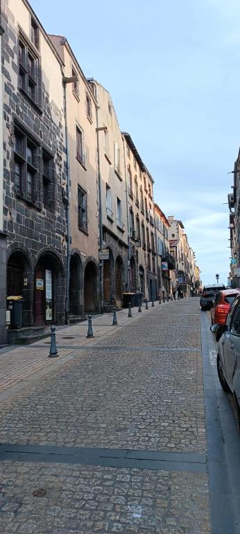 a cobblestone street with parked cars and buildings at Le Médiéval in Clermont-Ferrand