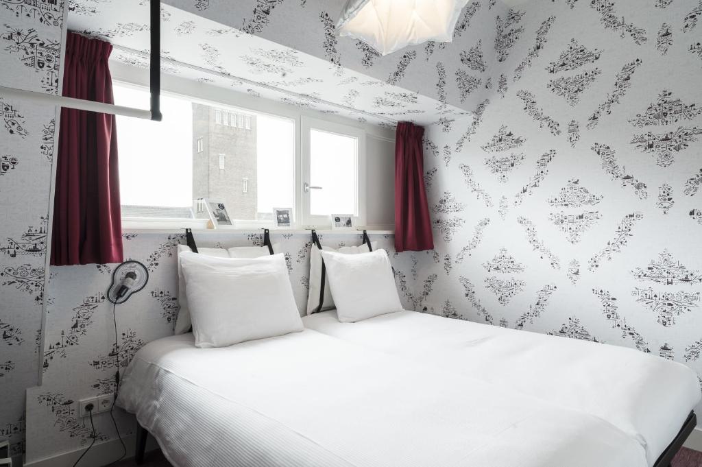 a bedroom with a white bed with red curtains at KABOOM Maastricht in Maastricht