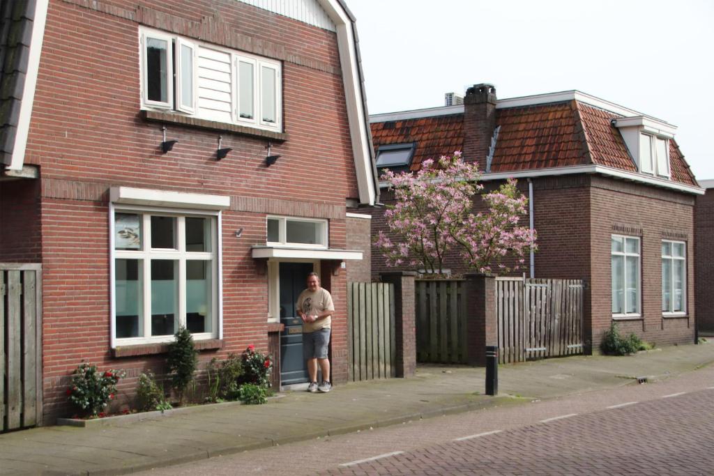 un homme debout à l'entrée d'une maison en briques dans l'établissement Boxtel, Appartement (1-4p) nabij station/centrum, à Boxtel