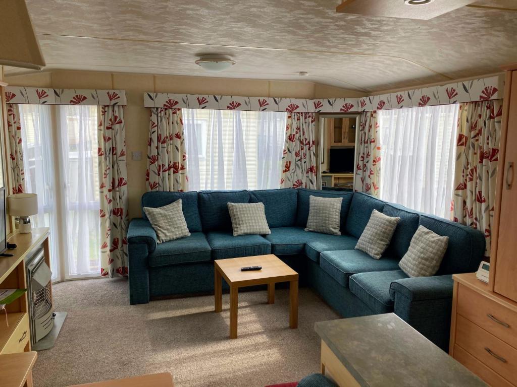 a living room with a blue couch and a table at Caravan hire Winthorpe Skegness in Skegness