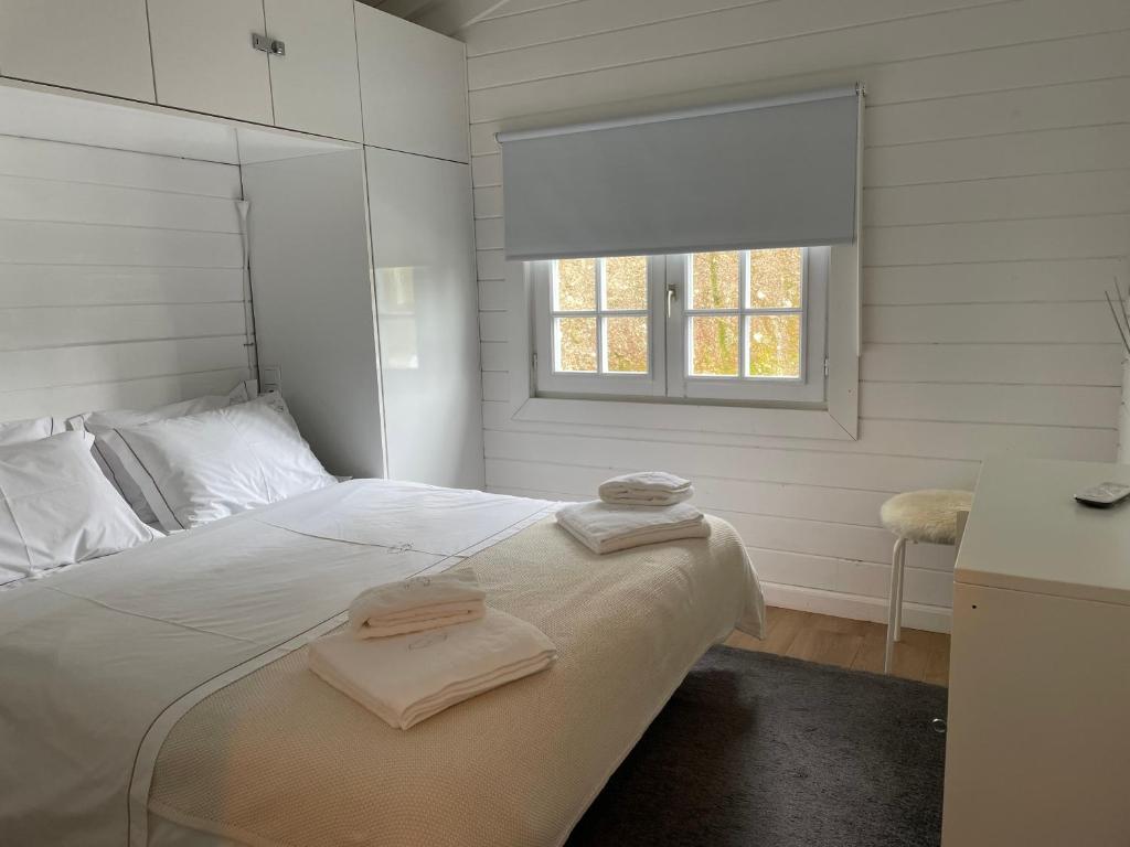 Un dormitorio blanco con una cama con toallas. en Chalé da Raposa, en Vieira do Minho