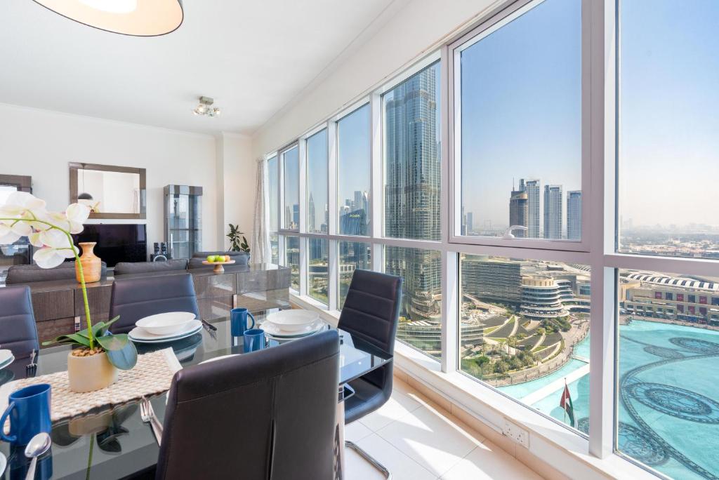 een woonkamer met een tafel en stoelen en een groot raam bij Incredible Fountain Views 2.5 BR Burj Residences in Dubai