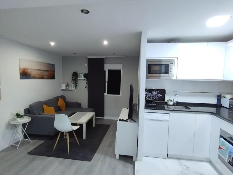 a kitchen and a living room with a couch and a table at Apartamento acogedor. in Gelves