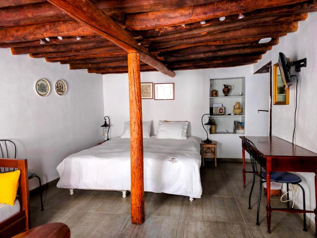 una camera da letto con un letto bianco e un soffitto in legno di Keresbino Hydra Art Suite a Hydra