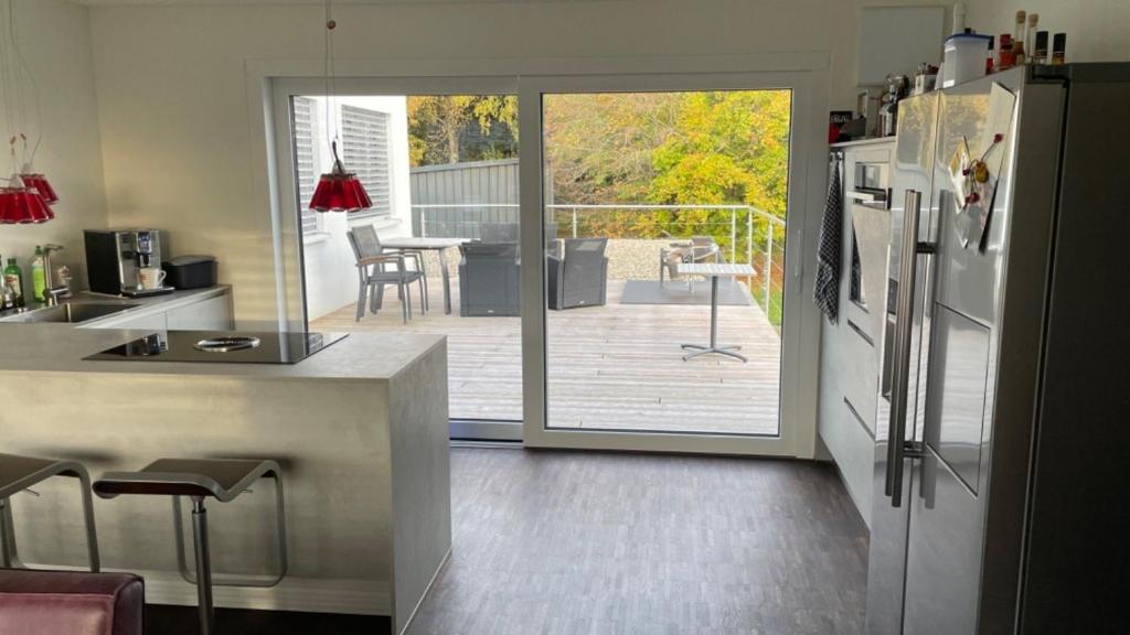 a kitchen with an open door to a patio with a refrigerator at Ferienhaus Rolf in Peterswald-Löffelscheid