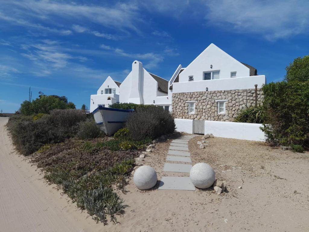 a white house on the beach with a path in the sand at Zeezicht Villa - Jacobsbaai in Jacobs Bay