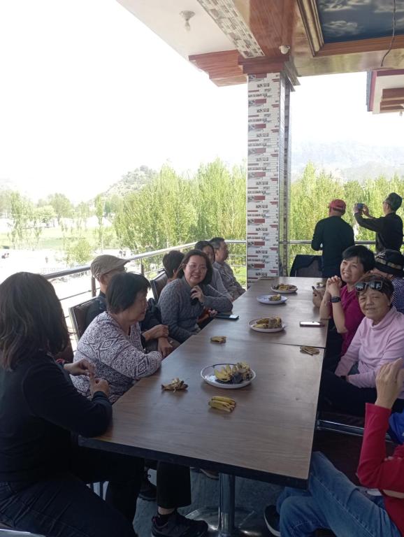 grupa ludzi siedzących przy stole w obiekcie River Breeze Family holiday home w mieście Swat
