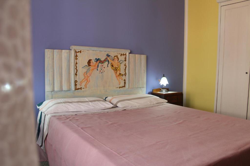 a bedroom with a bed with a painting above it at Donna Lucia in Giardini Naxos