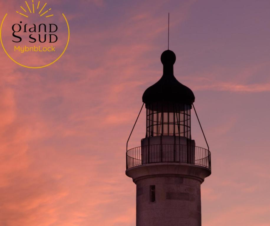 a lighthouse with a sunset in the background at Les Pieds dans le Sable in Le Grau-du-Roi