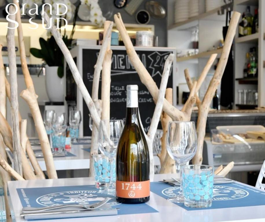 a bottle of wine sitting on a table with glasses at Les Pieds dans le Sable in Le Grau-du-Roi