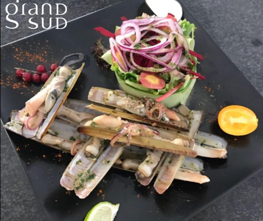 a plate of food with a salad and chop sticks at Les Pieds dans le Sable in Le Grau-du-Roi