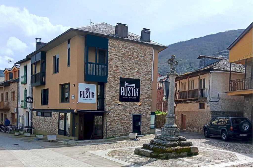 a building with a statue in the middle of a street at Rustik Hostal Rural in Molinaseca