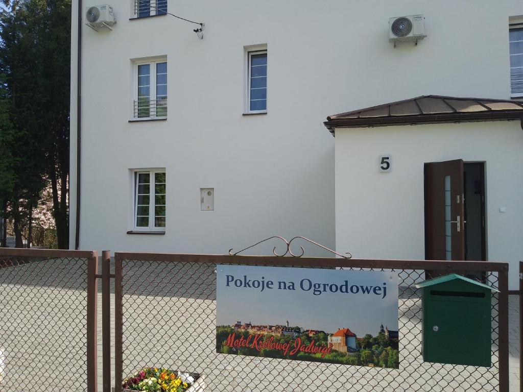 un cartel en una valla delante de una casa blanca en Motel Królowej Jadwigi Alicja Szymańska-Pokoje na Ogrodowej, en Sandomierz