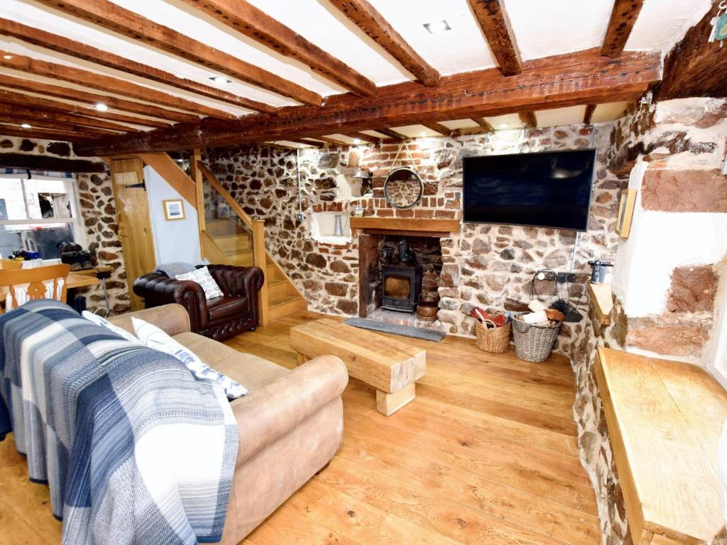 a living room with a stone fireplace and a tv at 1 Bed in Ravenglass 94503 in Ravenglass