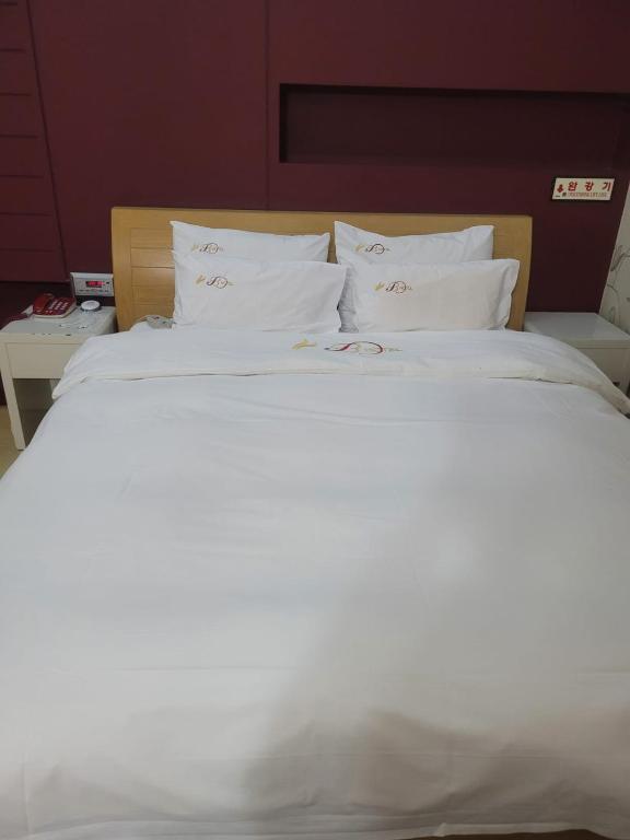 1 cama blanca grande con sábanas y almohadas blancas en B Hotel, en Cheonan