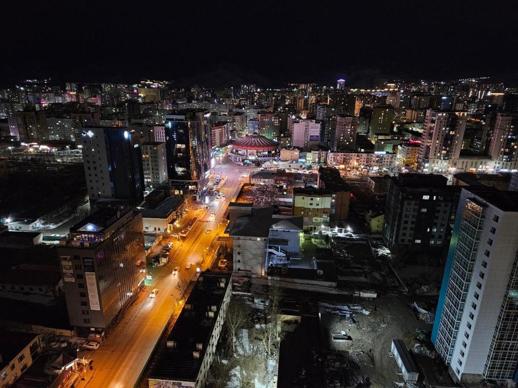 una ciudad iluminada por la noche con edificios y coches en Fully furnished apartment fantastic view city center, en Ulán Bator