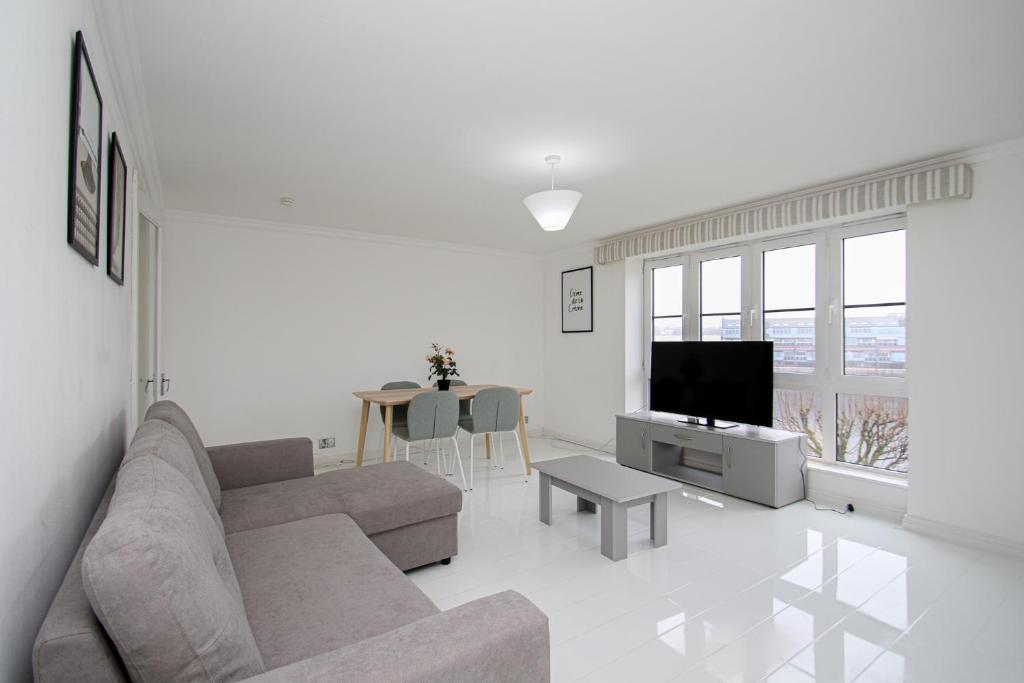 a white living room with a couch and a tv at Riverview Apartment in Glasgow