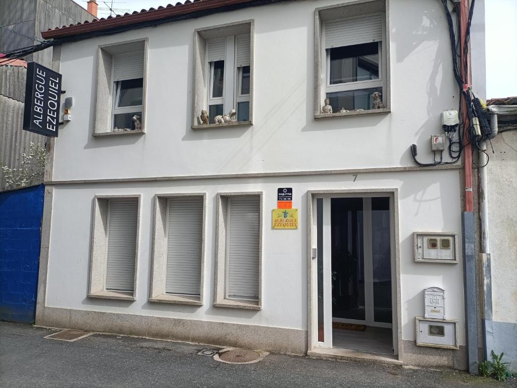 un edificio blanco con ventanas y una puerta en ALBERGUE EZEQUIEL, en Melide