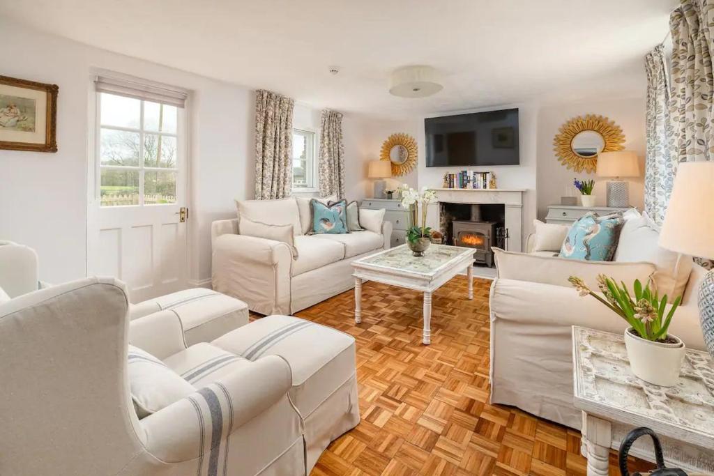 een woonkamer met witte meubels en een open haard bij Charming 4 Bed Cottage in Herts Countryside - Pass the Keys 