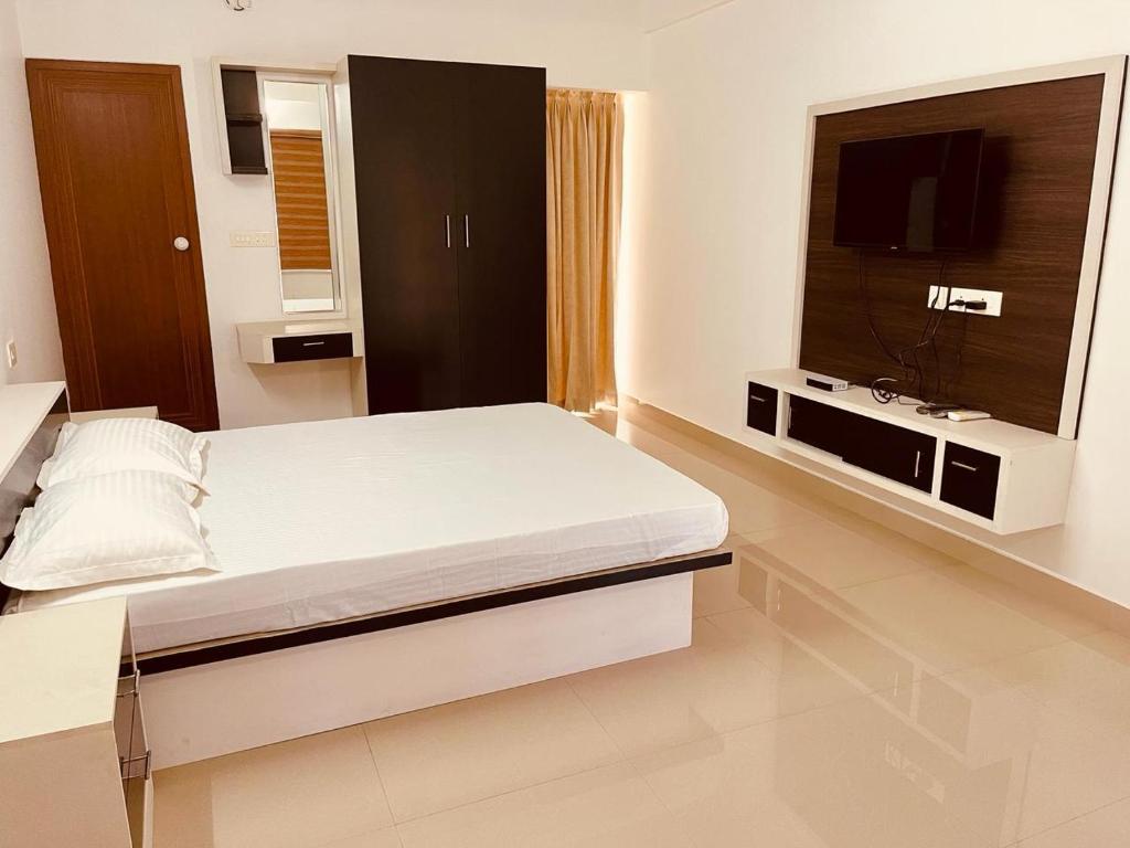 a bedroom with a bed and a flat screen tv at Amalas Lodge in Trivandrum