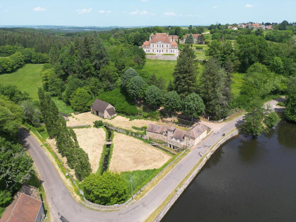 une vue aérienne d'une maison au bord d'une rivière dans l'établissement L'Ancien Moulin du Château de Marrault - Gîte de groupe, à Magny