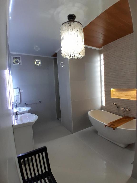 a bathroom with a tub and a sink and a chandelier at Villa Padi Pakem in Pakem