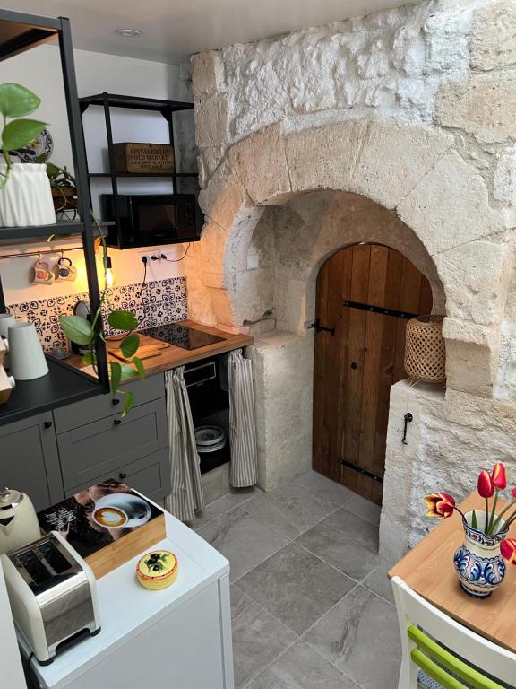 cocina con pared de piedra y puerta en Cosy apartment with swimming pool near Aubeterre, en Saint-Romain