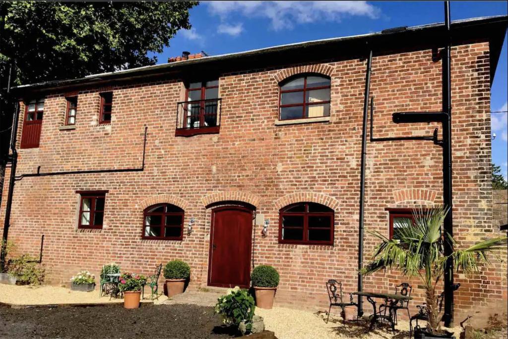 a brick building with a red door and a table at Evelith Manor Barns in Shifnal
