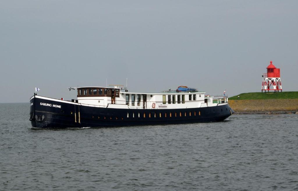 un barco en el agua con un faro en el fondo en Botel Sailing Home en Ámsterdam