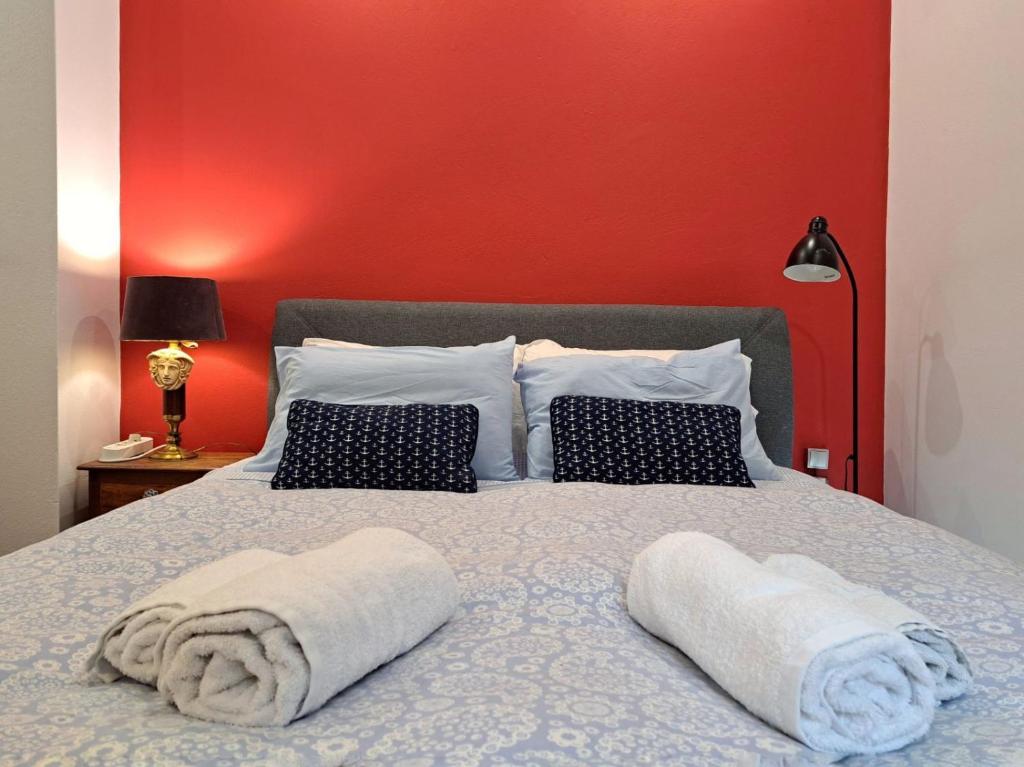 - un lit avec des serviettes et un mur rouge dans l'établissement GRAND BLUE SUITE DI GIORGIO 10min from Piraeus port, au Pirée