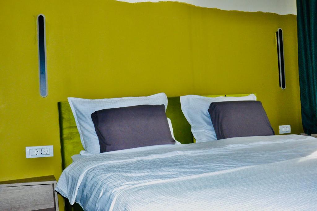 a bed with two pillows and a yellow wall at ESCAPE in Zăbala