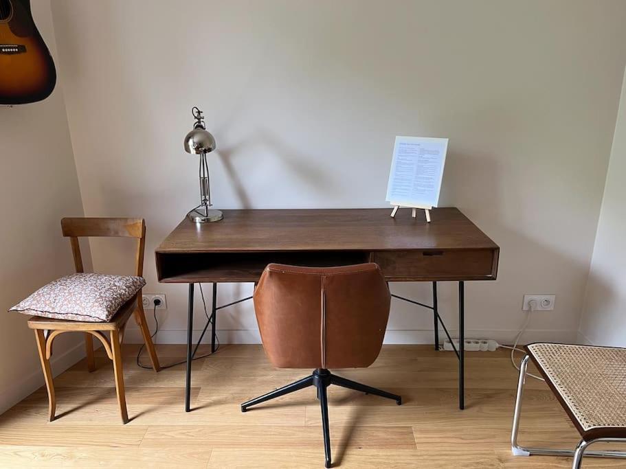 einen Holzschreibtisch mit einer Lampe und 2 Stühlen in der Unterkunft Studio agréable & charmant + WI-FI in Neuilly-sur-Seine