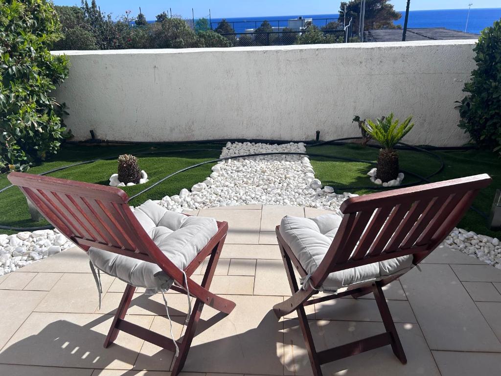 two chairs sitting on a patio with a garden at Grapevines Villas Makrygialos in Makry Gialos