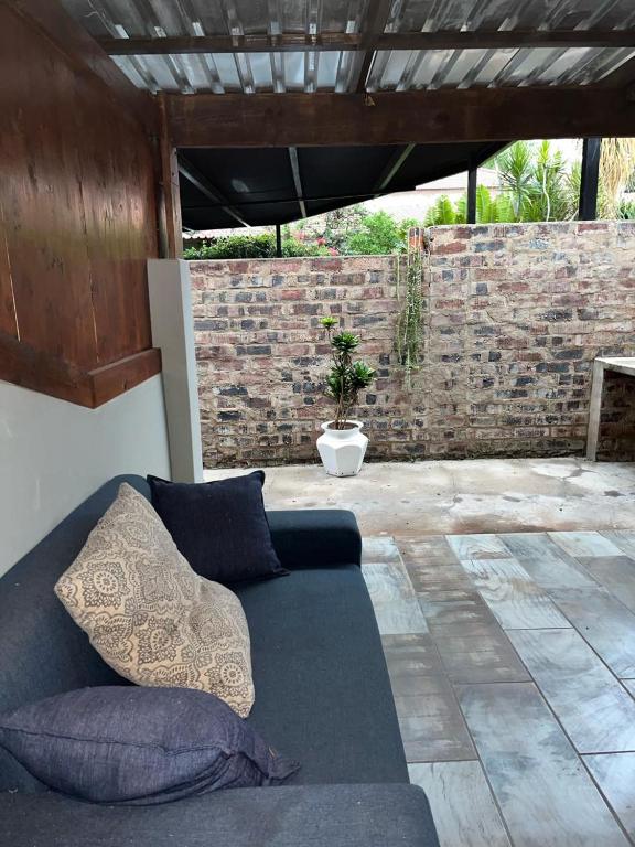 a couch sitting on a patio with a brick wall at @Eland B&B in Mokopane