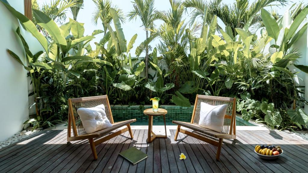 dos sillas y una mesa en una terraza con plantas en Premier Umalas Villas en Kerobokan