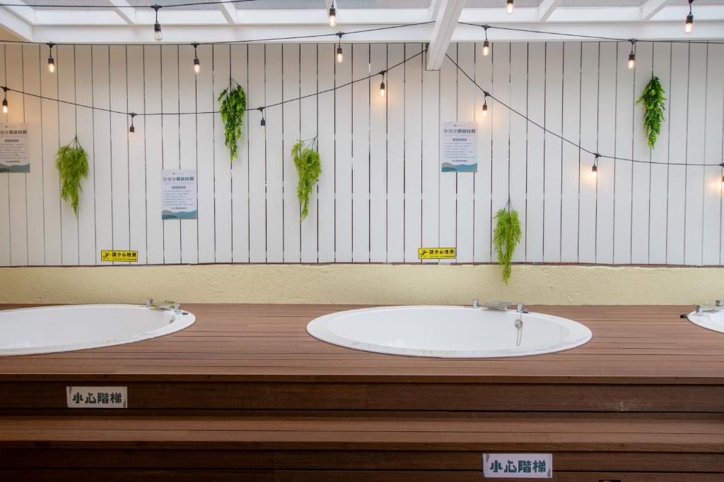 three sinks in a bathroom with plants on the wall at Ashare Hotel in Jiaoxi