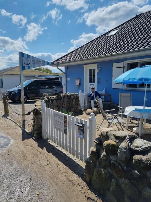 a blue house with a fence and a table at Strandhaus in der Düne in Dierhagen