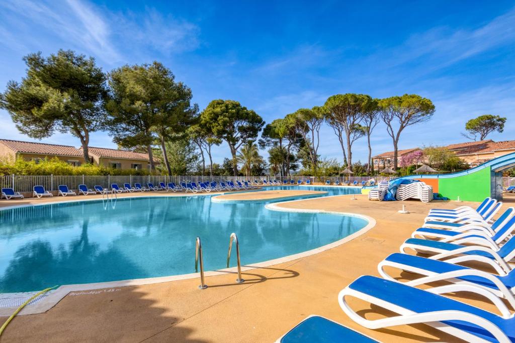 une grande piscine avec des chaises longues et des arbres dans l'établissement Maison - Residence avec piscine, à Calvisson