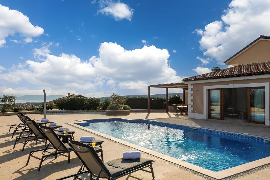einen Pool mit Stühlen und ein Haus in der Unterkunft Villa Vilani Spa & Pool - Happy Rentals in Crikvenica