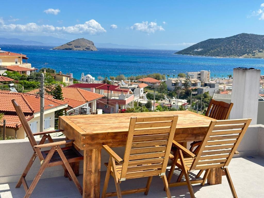 einen Holztisch und Stühle auf einem Balkon mit Meerblick in der Unterkunft Kasaj Luxury Apartments in Porto Rafti