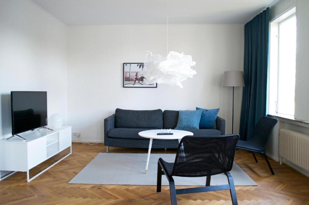 uma sala de estar com um sofá azul e uma televisão em Basement Lounge em Halmstad