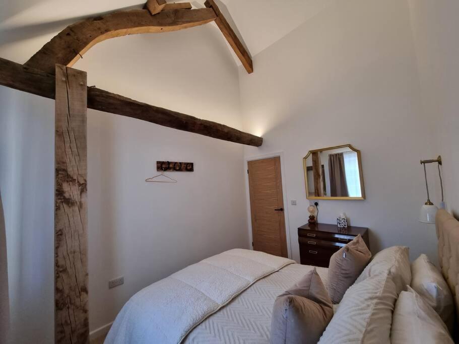 a bedroom with a white bed and a couch at Blacksmiths Cottage in Brompton