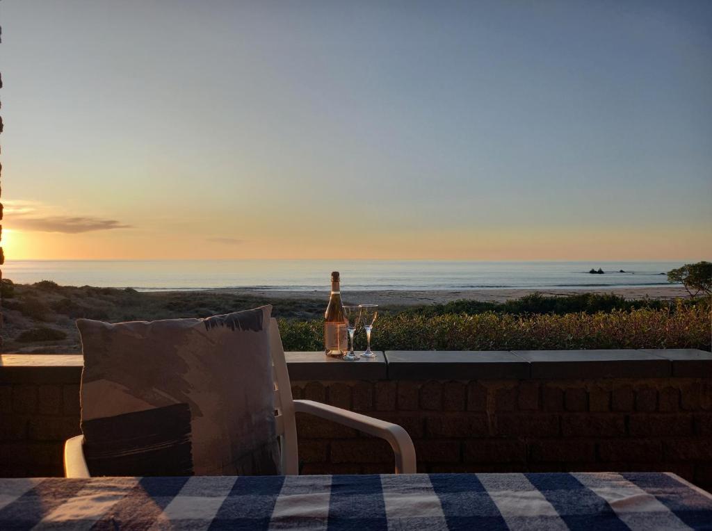 Una botella de vino sentada en una mesa con vistas al océano en Beach Haven Cottage, en Britannia Bay