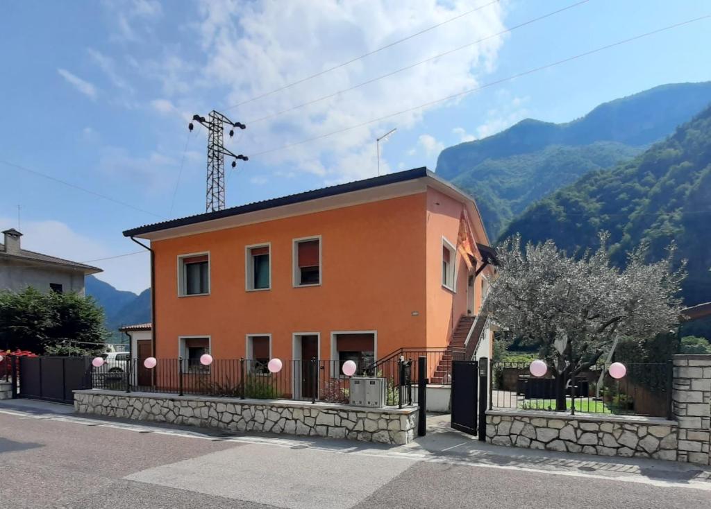 una pequeña casa naranja con montañas en el fondo en Terra di Mezzo en Valbrenta 