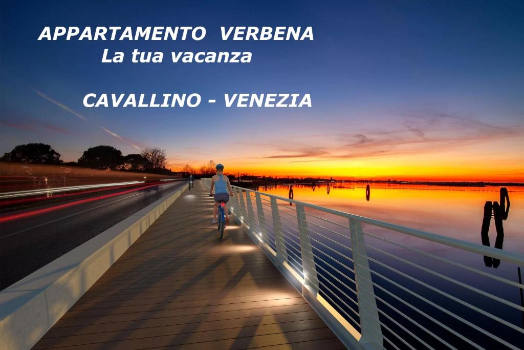 una persona montando una bicicleta en un puente al atardecer en Elegante appartamento con vista a Cavallino Venezia en Cavallino-Treporti