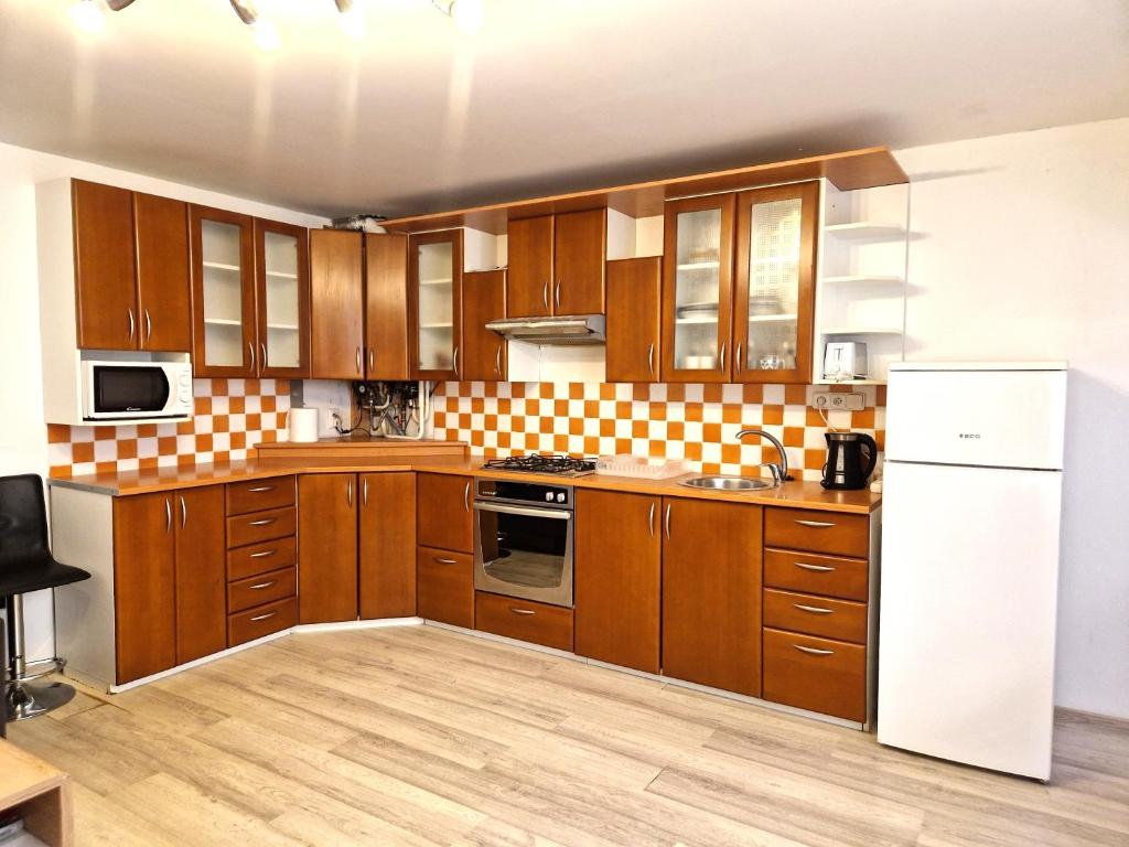 eine Küche mit Holzschränken und einem weißen Kühlschrank in der Unterkunft Apartmány Drážovce in Nitra