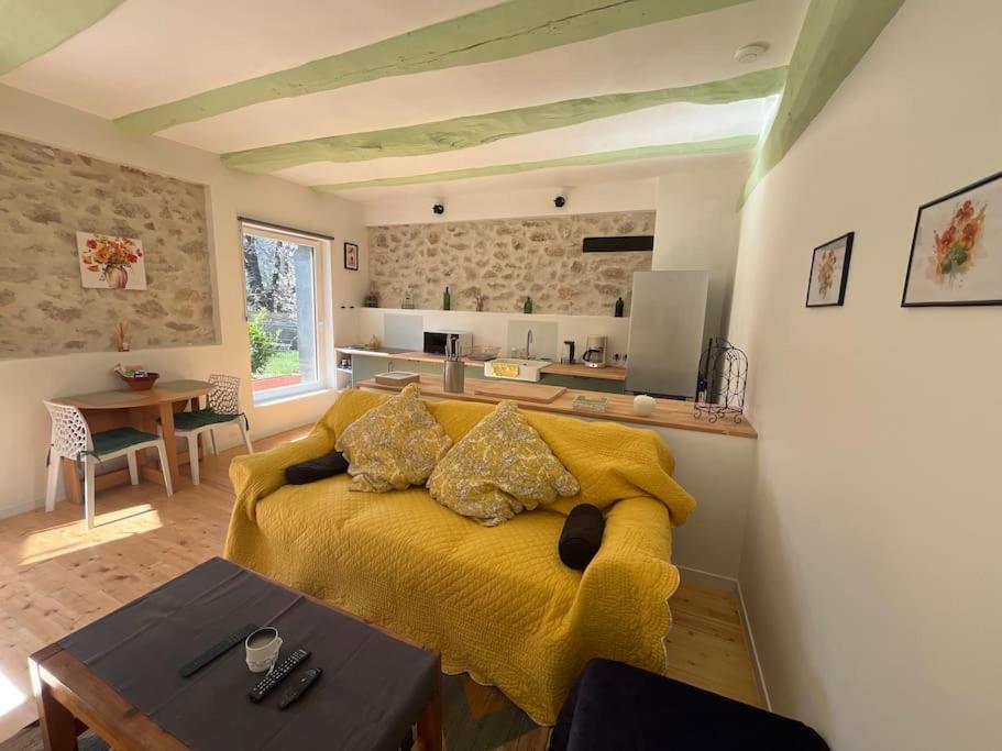 uma sala de estar com uma cama amarela e uma cozinha em Appartement Les Capucines em Villecroze