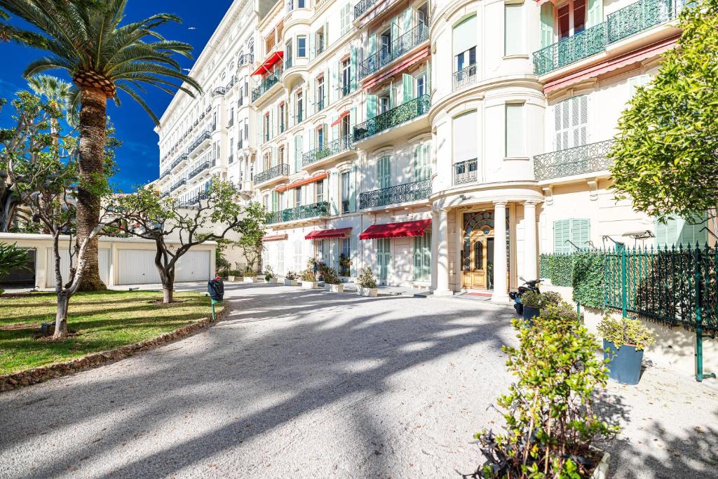 une rue en face d'un bâtiment avec un palmier dans l'établissement Regina - Happy Rentals, à Menton