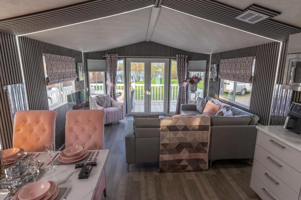 een woonkamer met een bank en een tafel bij Tattershall VIP Retreat - Hot tub, stunning lakeside views, newly refurbished to an amazing 5 star standard in Tattershall